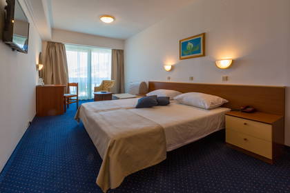 Pokój hotelowy z dwoma łóżkami, biurkiem i balkonem.