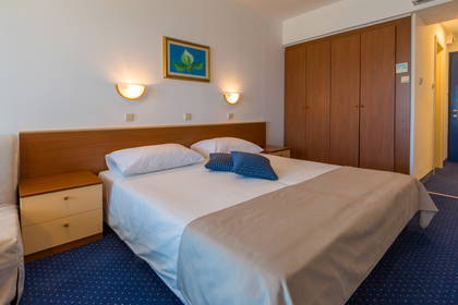 Pokój hotelowy z łóżkiem, szafkami nocnymi i szafą.