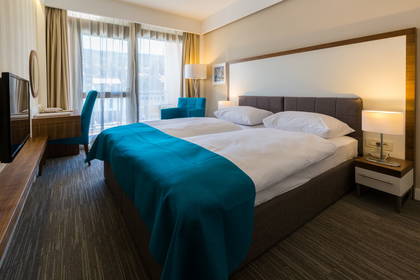 Pokój hotelowy z łóżkiem małżeńskim, biurkiem i balkonem.