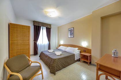 Pokój hotelowy z łóżkiem, krzesłem i stolikiem nocnym.