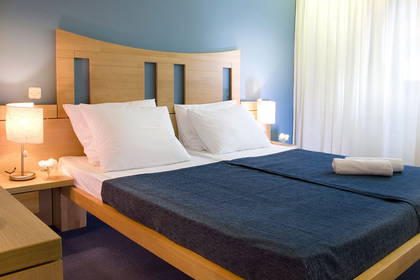 Pokój hotelowy z łóżkiem, telewizorem i szafką nocną.