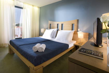 Pokój hotelowy z łóżkiem małżeńskim, telewizorem i balkonem.