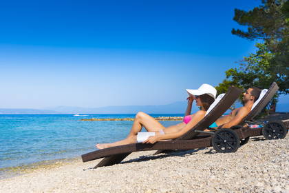 Para relaksuje się na plaży, leżąc na leżakach.