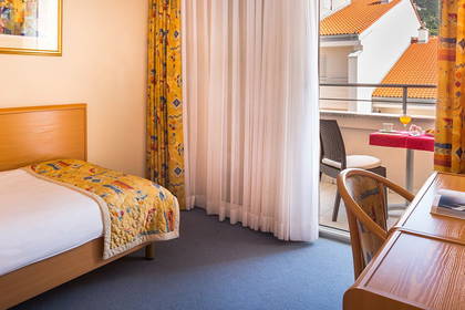 Pokój hotelowy z łóżkiem, biurkiem i balkonem.