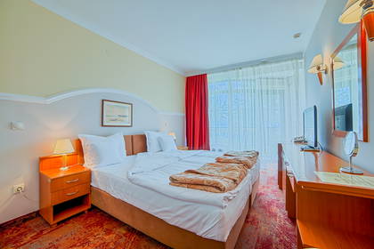Pokój hotelowy z dwoma łóżkami, szafką nocną i telewizorem.