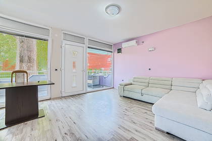 Jasny salon z kanapą, biurkiem i balkonem.
