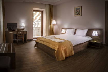 Pokój hotelowy z łóżkiem, biurkiem i balkonem.
