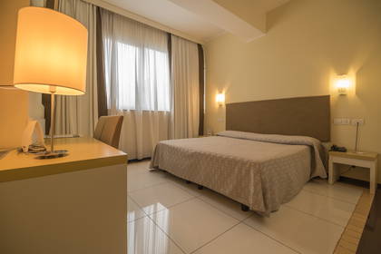 Pokój hotelowy z biurkiem, łóżkiem i oknem.