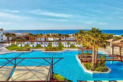 Basen hotelowy z palmami i stolikami.