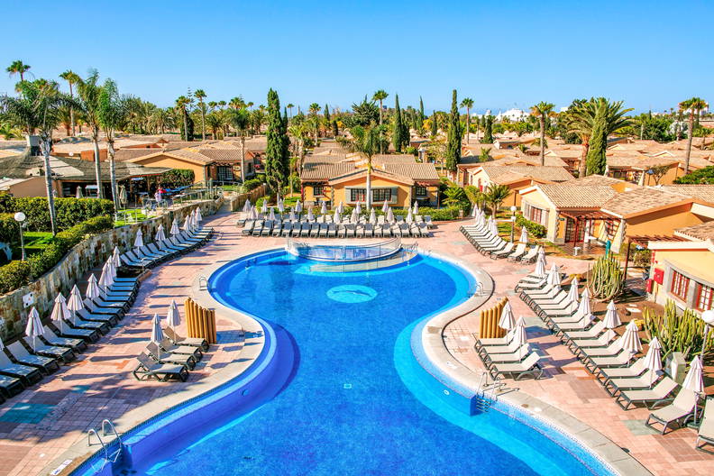 Basen w kształcie ósemki z leżakami i parasolami, widok z góry.