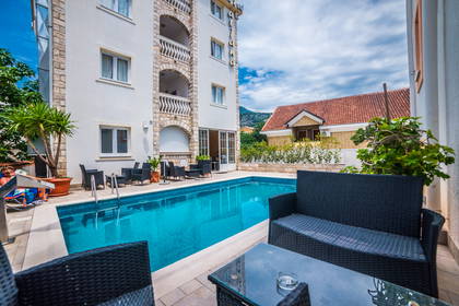 Hotelowy basen z turkusową wodą i czarnymi meblami wypoczynkowymi.