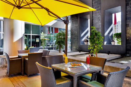 Stolik z napojami i przekąskami pod żółtym parasolem w restauracji na zewnątrz.