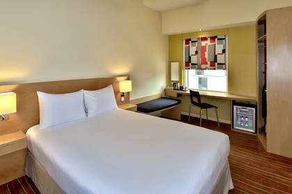 Pokój hotelowy z łóżkiem, biurkiem i oknem.