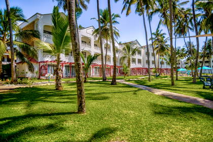 Hotel w tropikalnym kurorcie z palmami i trawnikiem.