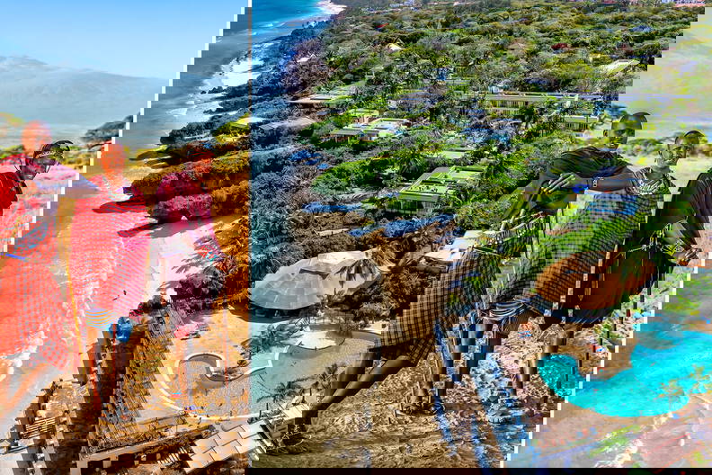 Trzej Masajowie na tle Kilimandżaro i luksusowy kurort na plaży.