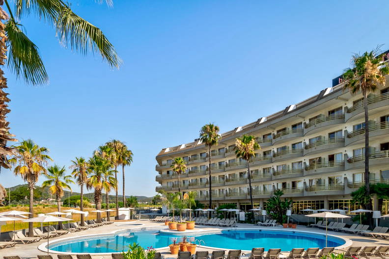 Hotel z basenem, palmami i leżakami do opalania.