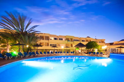 Hotelowy basen z leżakami, w tle budynek hotelowy.