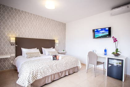 Pokój hotelowy z łóżkiem, biurkiem, telewizorem i kwiatami.
