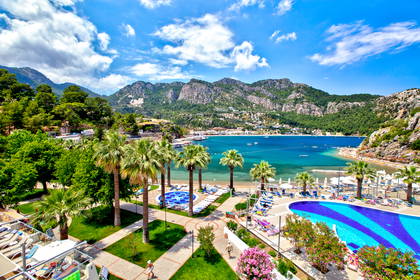 Widok z góry na basen, palmy, plażę i góry w tureckim Marmaris.