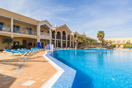 Basen hotelowy z leżakami. W tle budynek.