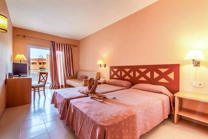 Pokój hotelowy z dwoma łóżkami, balkonem i sofą.
