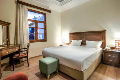 Pokój hotelowy z łóżkiem, toaletką i zielonym stołem.