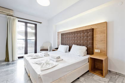 Jasny pokój hotelowy z dużym łóżkiem i balkonem.