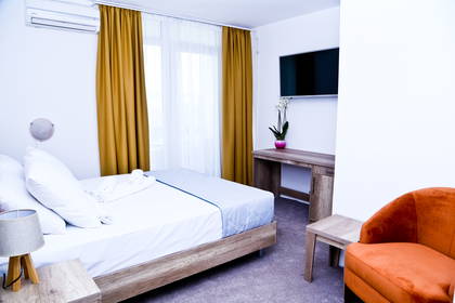 Pokój hotelowy z łóżkiem, biurkiem, telewizorem i fotelem.