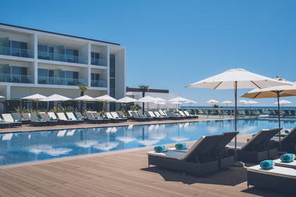 Basen z leżakami i parasolami przy hotelu.