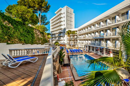 Hotel z basenem otoczonym palmami w słoneczny dzień.