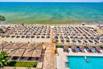 Widok z góry na plażę z parasolami, basen i morze.
