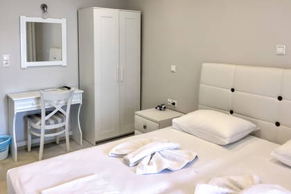 Jasny pokój hotelowy z łóżkiem, biurkiem i szafą.