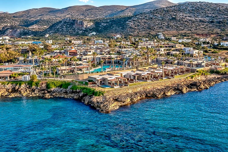 Widok z góry na nadmorski kurort. W tle góry i błękitna woda.