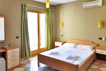 Pokój hotelowy z łóżkiem, szafkami nocnymi i balkonem.