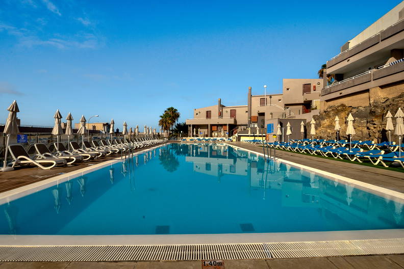 Basen z leżakami i parasolami w ośrodku wypoczynkowym.