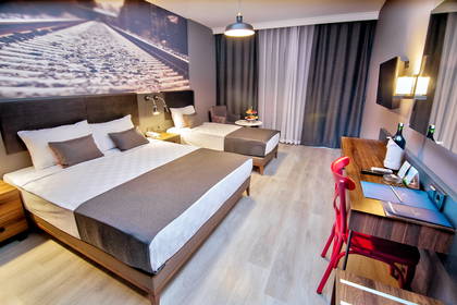 Pokój hotelowy z dwoma łóżkami, biurkiem i krzesłem.