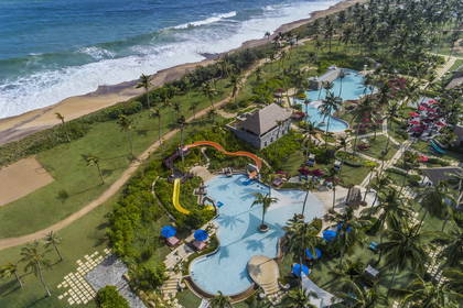 Resort z basenami, palmami i plażą, widok z lotu ptaka.