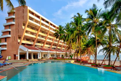 Hotel z basenem i palmami blisko plaży.