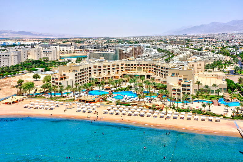 Hotel z basenami i plażą widziany z góry.