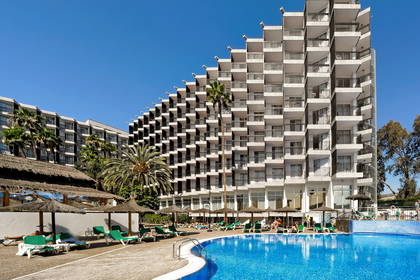 Hotel z balkonami, basenem i leżakami do opalania.
