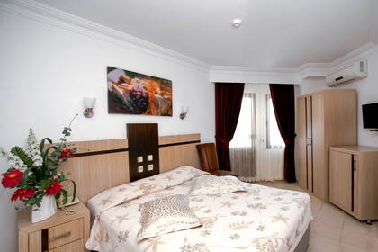 Pokój hotelowy z łóżkiem, szafą i zasłonami w oknach.