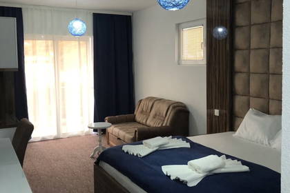 Pokój hotelowy z łóżkiem, sofą i niebieskimi lampkami.