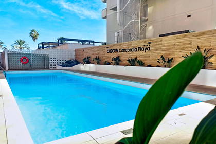 Basen w hotelu Checkin Concordia Playa w słoneczny dzień.
