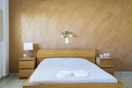 Pokój hotelowy z drewnianym łóżkiem i szafkami nocnymi.