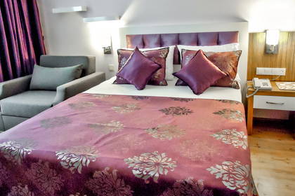 Pokój hotelowy z łóżkiem, fotelem i szafką nocną.