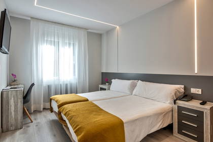 Pokój hotelowy z dwoma łóżkami, biurkiem i oknem.