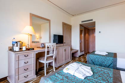 Pokój hotelowy z dwoma łóżkami, biurkiem i telewizorem.