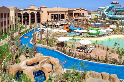 Park wodny z licznymi atrakcjami i budynkami hotelowymi w tle.