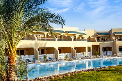 Hotel z basenem otoczonym palmami.