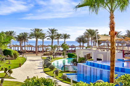 Resort z basenami, palmami i widokiem na morze.